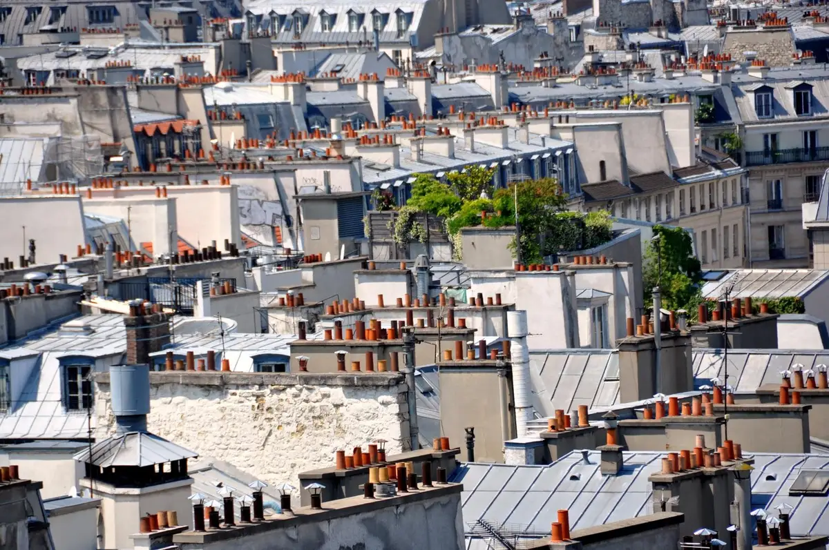 Toits en zinc et souches de cheminée en terre cuite d'immeubles parisiens vus depuis un étage élevé